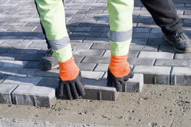 Concrete contractor placing brick pavers by hand for residential driveway installation in North Ridgeville, OH