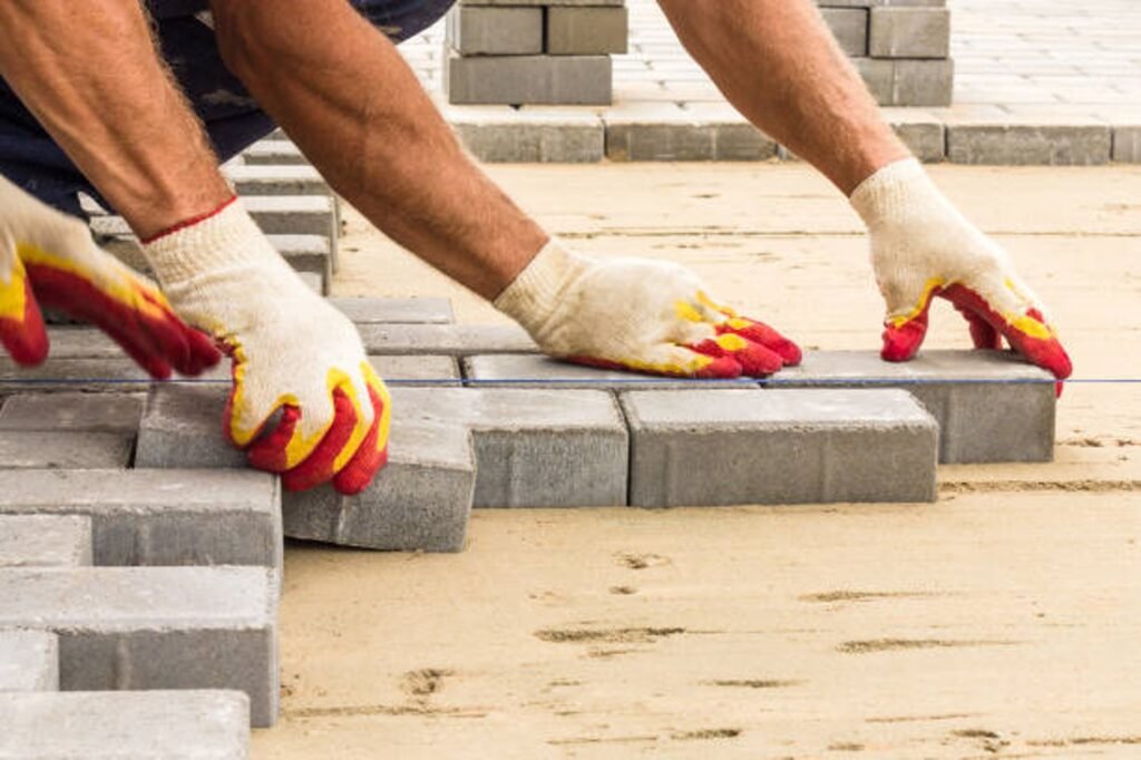 Contractor installing concrete pavers for patio construction on a leveled sand base in Medina, OH